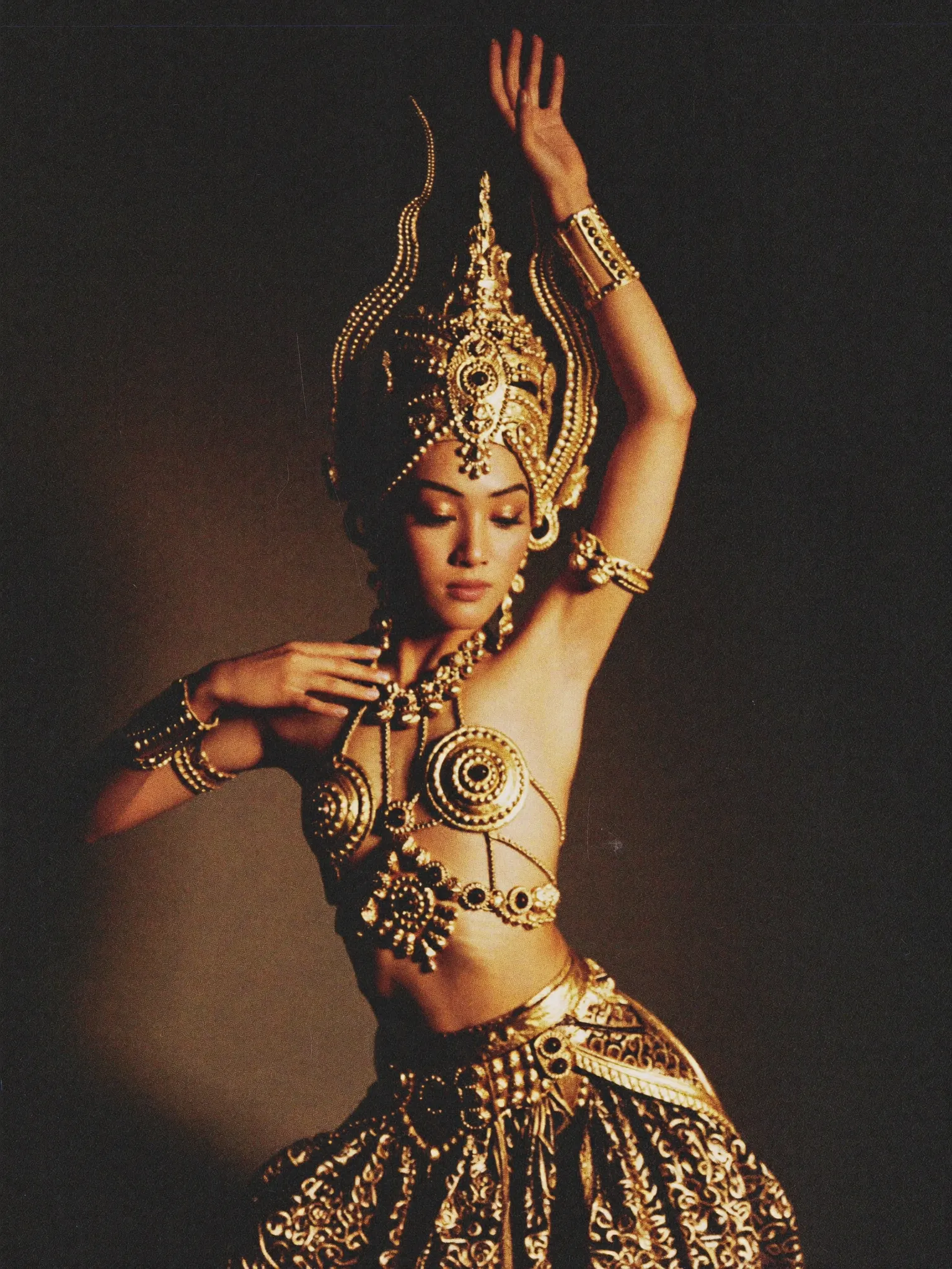 A classical Javanese dancer in an ornate gold costume mid-gesture